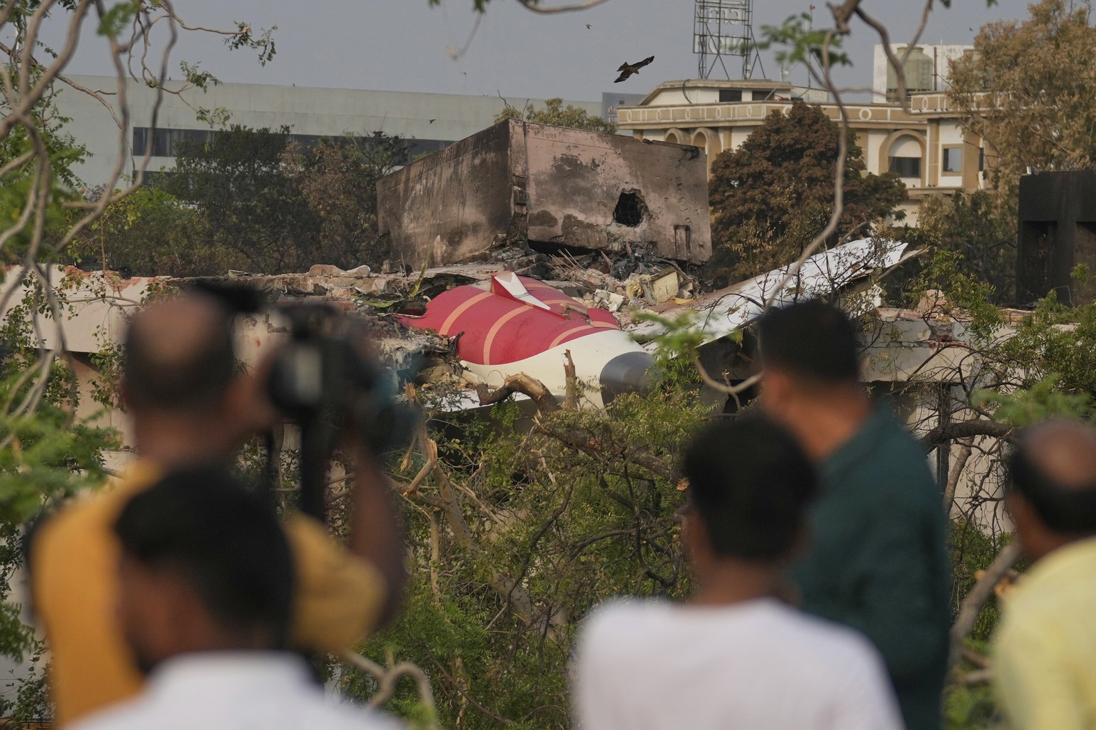 Onlookers watch wreckage from Thursday&#039;s Air India plane crash lying atop a building in Ahmedabad, India, Saturday, June 14, 2025. (AP Photo/Rafiq Maqbool)
India Plane Crash