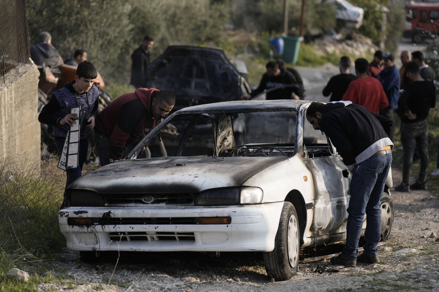 Palestinians inspect a burnt car, which residents say was set on fire by Israeli settlers, in Burin village near the West Bank city of Nablus, Saturday, Feb. 25, 2023. Palestinian officials say settle ...