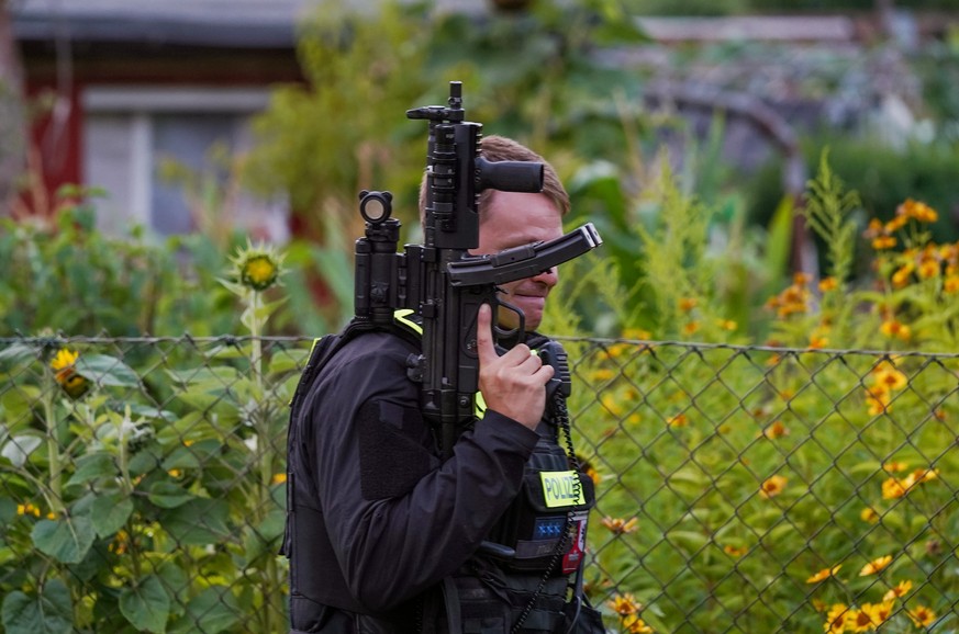 epa13134587 A police officer armed with a machine pistol stands at the scene of an operation in an allotment garden community in Berlin's Spandau district following a car-ramming attack near the  ...
