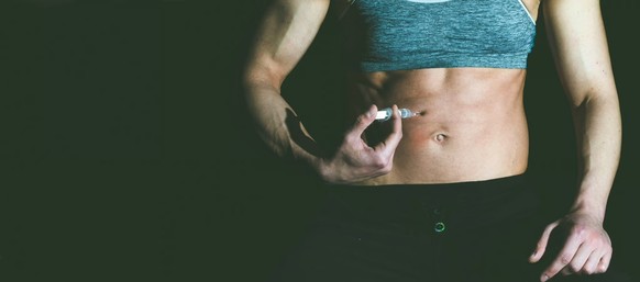 Une femme adepte de musculation s'injecte un produit dopant dans l'abdomen. Les femmes aussi ont de plus en plus souvent recours aux stéroïdes anabolisants.