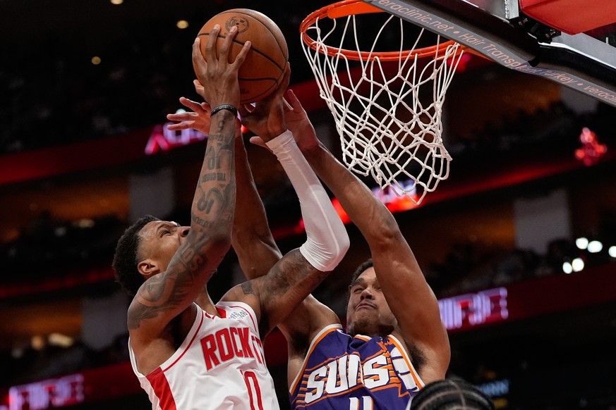 Houston Rockets guard Aaron Holiday (0) shoots against Phoenix Suns forward Oso Ighodaro (11) during the second half of an NBA basketball game in Houston, Friday, Dec. 5, 2025. (AP Photo/Ashley Landis ...