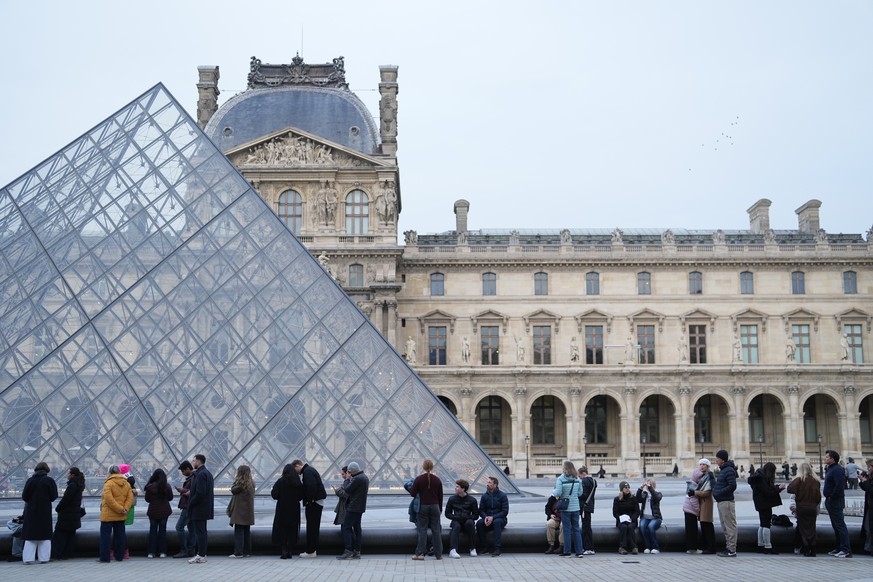 FILE - People wait for the Louvre museum to open as employees at the Louvre Museum vote to extend a strike that has disrupted operations at the world's most visited museum, Thursday, Dec. 18, 202 ...