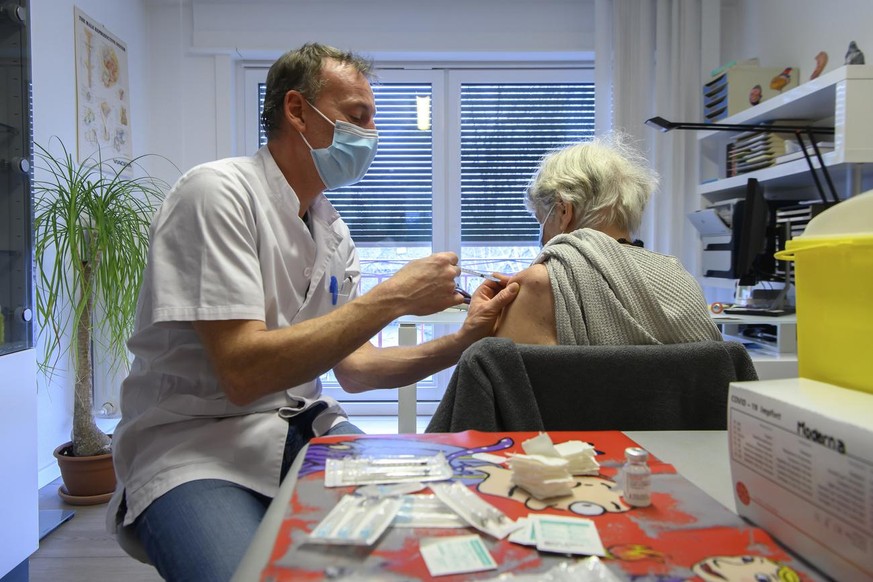 Le Dr. Amstutz vaccine une patiente a l&#039;aide du vaccin de Moderna contre la Covid-19, dans son cabinet medical, pendant la pandemie de Coronavirus (Covid-19), ce mardi 9 fevrier 2021, a Estavayer ...