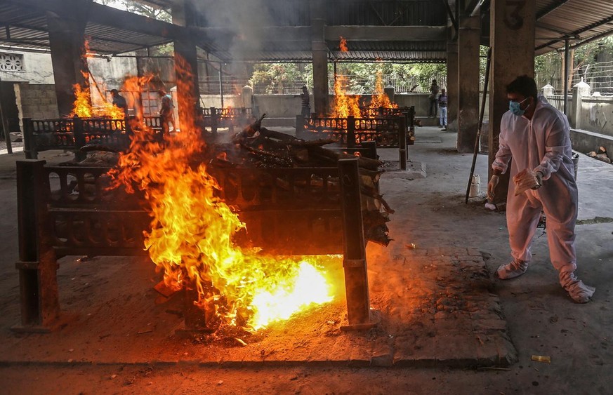 epa09154510 Relatives and municipal workers wearing personal protective equipment (PPE) perform the last rites for COVID-19 victims during their funeral at a cremation ground in Virar West, on the out ...