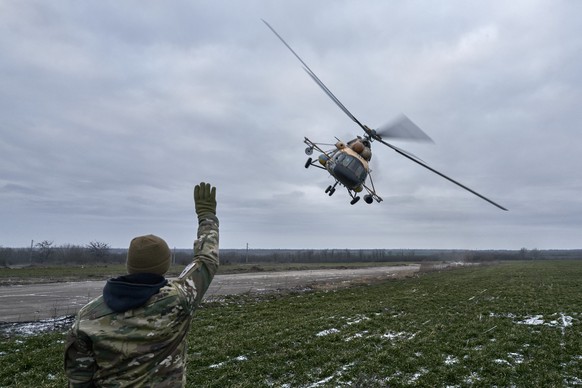 A Ukrainian soldier waves to a military helicopter returning from the combat, close to the frontline in the Kherson region, Ukraine, Sunday, Jan. 8, 2023. (AP Photo/LIBKOS)