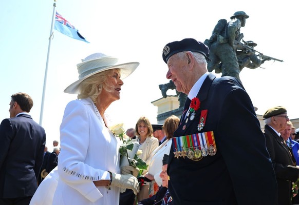 VER-SUR-MER, FRANCE - JUNE 06: Queen Camilla receives a white rose from a veteran during the UK Ministry of Defence and the Royal British Legion’s commemorative event at the British Normandy Memorial ...