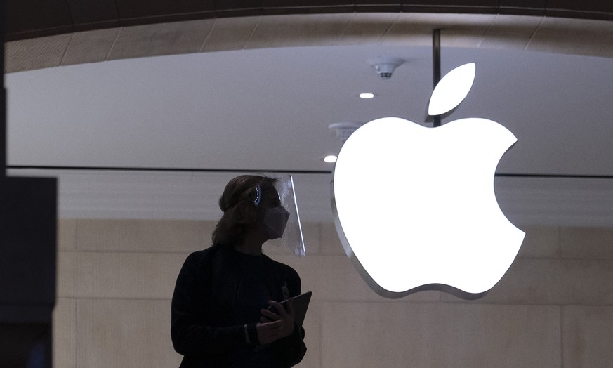 In this Feb. 5, 2021 photo, an Apple store employee is shown in New York. Apple on Wednesday, Sept. 1, is relaxing rules to allow some app developers such as Spotify, Netflix and digital publishers to ...