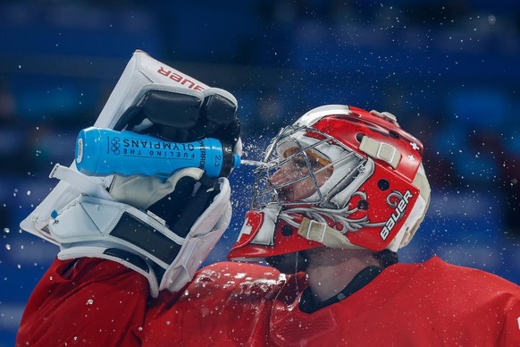 epa09750106 Goalkeeper Reto Berra of Switzerland sprays water on his face during the Men&#039;s Ice Hockey preliminary round match between Switzerland and Denmark at the Beijing 2022 Olympic Games, Be ...