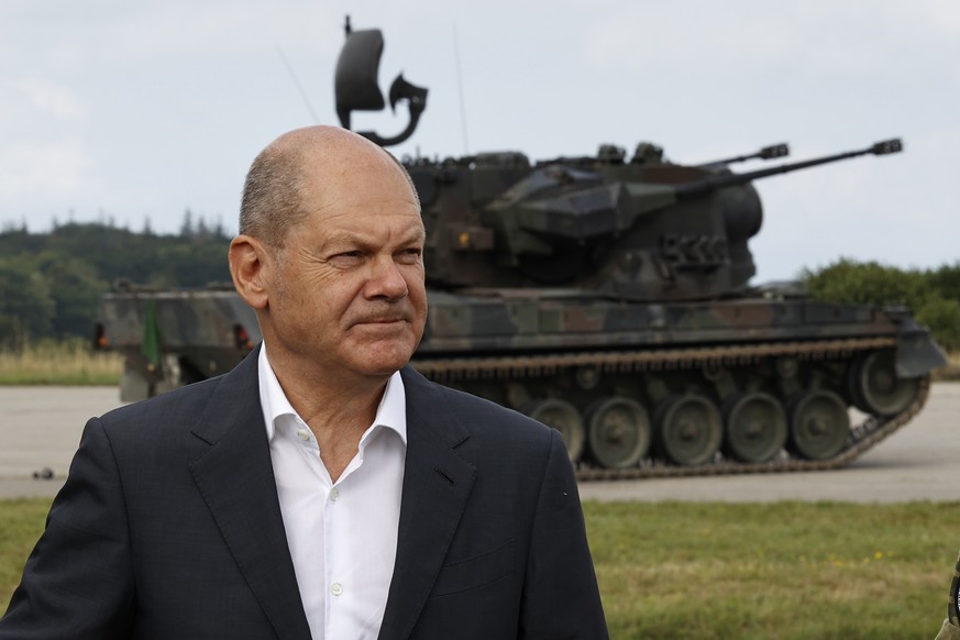 epa10137736 German Chancellor Olaf Scholz poses in front of an anti-aircraft gun tank Gepard during his visit a training facility of the arms-maker Krauss-Maffei Wegmann at the Putlos military trainin ...