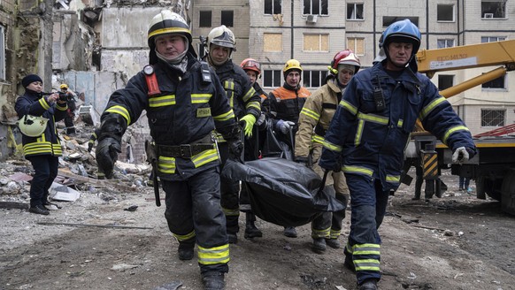 Rescue workers carry the body of a man who was killed in a Russian missile strike on an apartment building in the southeastern city of Dnipro, Ukraine, Monday, Jan. 16, 2023. (AP Photo/Evgeniy Malolet ...