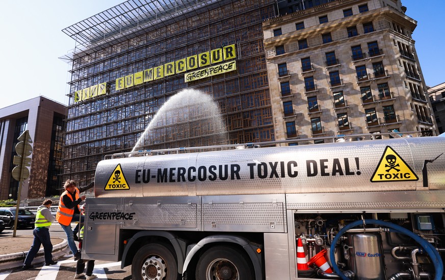 epa10652136 A Greenpeace activist sprays water to simulate pesticides as other activists climb the Europa building on the main European Council headquarters building ahead of the EU trade ministers co ...