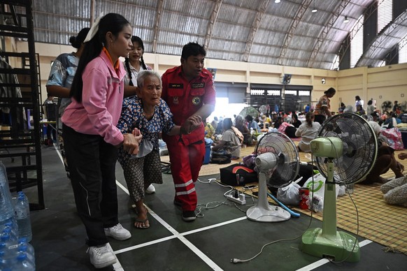 An elderly evacuee is assisted as they take shelter in a gymnasium on the grounds of Surindra Rajabhat University in the Thai border province of Surin on July 25, 2025. More than 100,000 people have f ...