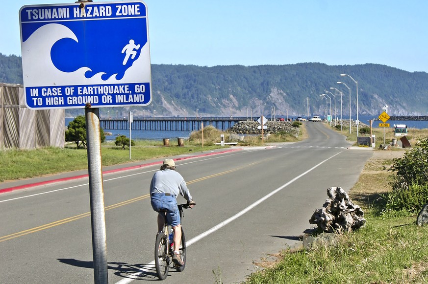 FILE - A cyclist rides toward the B Street Pier past a tsunami hazard sign in Crescent City, Calif., about 25 miles south of the California/Oregon border, on July 7, 2005. The California Geological Su ...