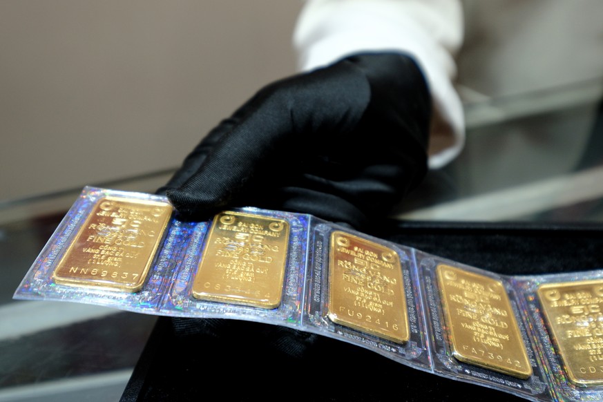 epa11269014 A saleswoman picks up gold bars at a jewelry shop in Hanoi, Vietnam, 10 April 2024. The price of gold in Vietnam has soared to record high price recently. Vietnamese Prime Minister Pham Mi ...