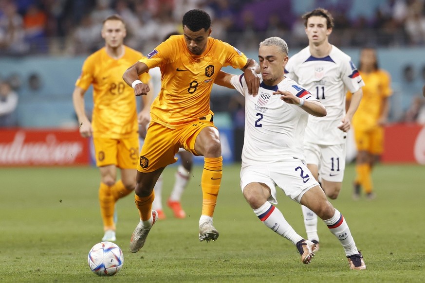 epa10346356 Cody Gakpo of the Netherlands in action against Sergino Dest (R) of the US during the FIFA World Cup 2022 round of 16 soccer match between the Netherlands and the USA at Khalifa Internatio ...