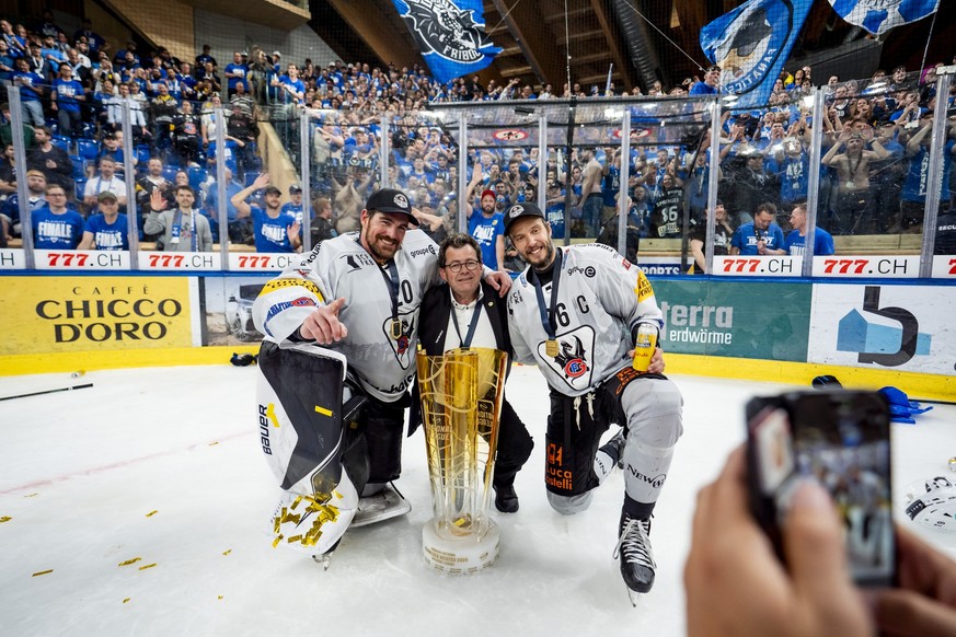 Torhueter Reto Berra, Hubert Waeber, Praesident von Fribourg-Gotteron und Julien Sprunger (HCFG) feiern den Meistertitel mit dem Pokal nach ihrem Sieg gegen Davos in der Verlaengerung im siebten Eisho ...