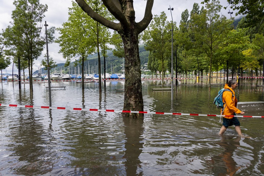 epa09348752 A man walks in the lake water in the harbor as the water level of the Bielersee rose following heavy rainfall over the past few days in Biel, Switzerland, 16 July 2021. The water level of  ...