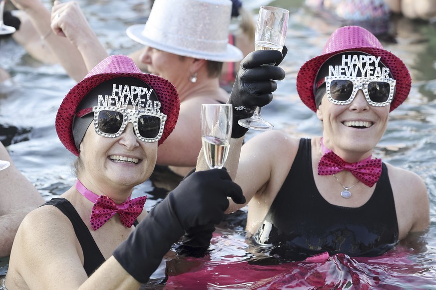 People toast with champagne while swimming in the cold water during the New Year&#039;s traditional swimming in the Lake of Geneva at the Bains des Paquis in Geneva, Switzerland, Sunday, Jan. 1, 2023. ...