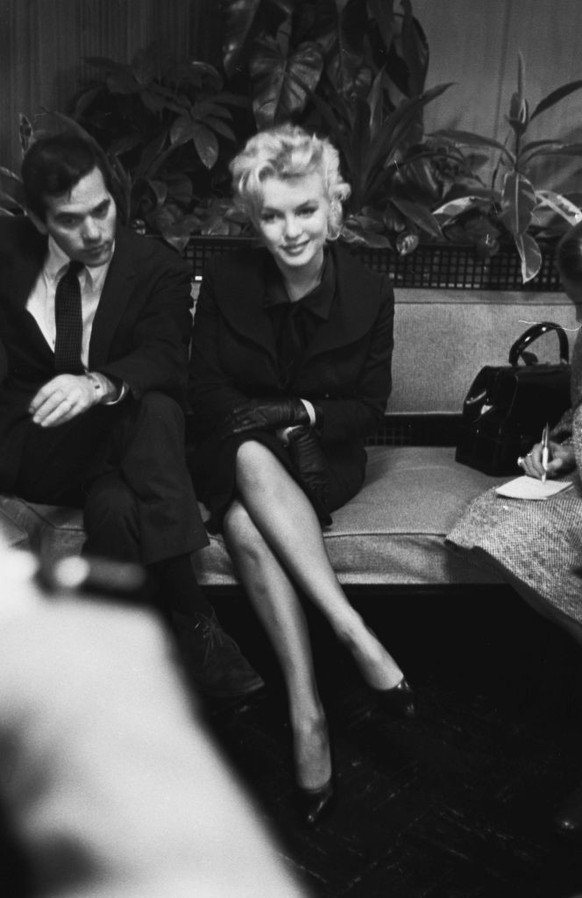 American photographer Milton H Greene (1922-1985) accompanies American actress Marilyn Monroe (1926-1962), wearing a black suit with black leather gloves and a black satin blouse and tie. as she atten ...