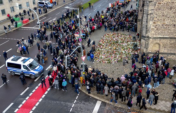 People gather to lay flowers and light candles at the entrance of Johannis church near the Christmas Market, where a car drove into a crowd on Friday evening, in Magdeburg, Germany, Sunday, Dec. 22, 2 ...