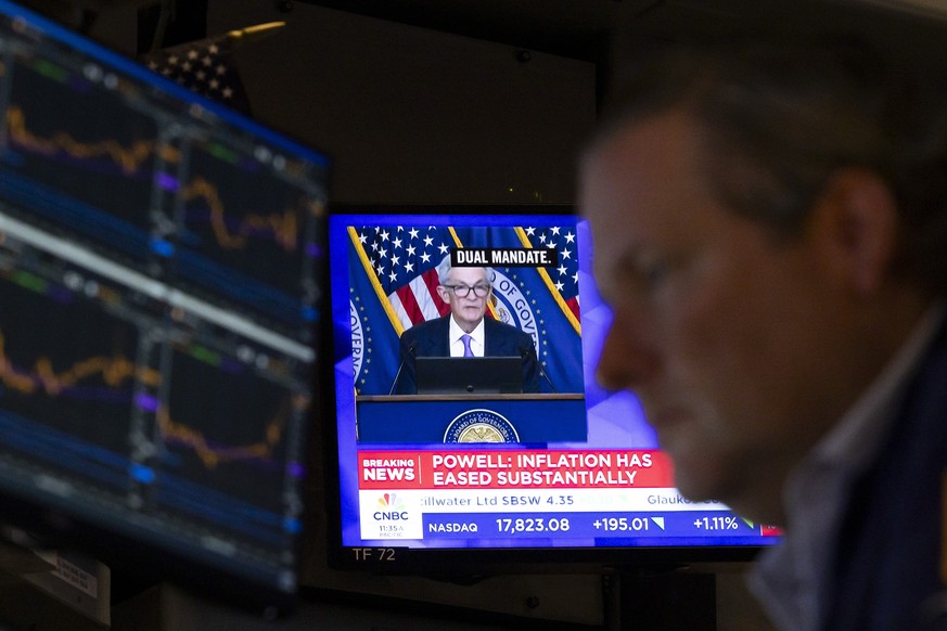 epa11612588 Traders work on the floor as a screen shows US Federal Reserve Chairman Jerome Powell speaks during a press conference following news of the Federal Reserve decision lower interest rates f ...