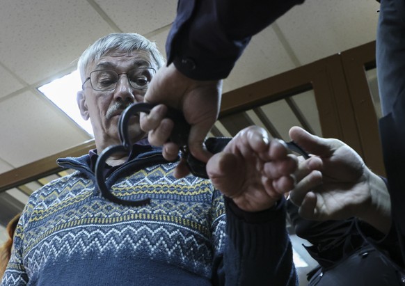 epa11184124 Russian policeman puts handcuffs on Human rights activist and chairman of the Human Rights Center &#039;Memorial&#039;, Oleg Orlov after verdict was announced at the court hearing at the G ...