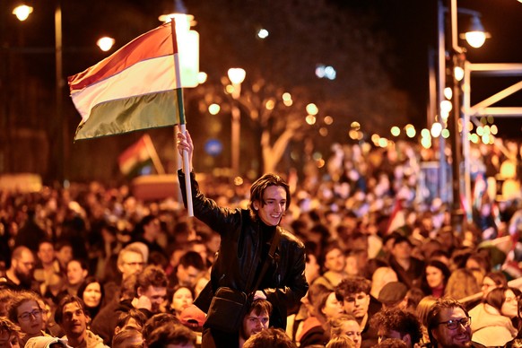 A man waves a Hungarian flag as he celebrates in the streets after the announcement of partial results of the Hungarian parliamentary in Budapest, Hungary, Sunday, April 12, 2026. (AP Photo/Denes Erdo ...