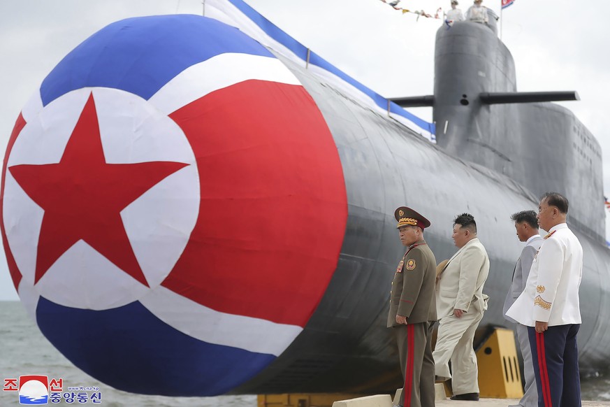 In this photo provided by the North Korean government, North Korea leader Kim Jong Un, second left, looks at what is says a new nuclear attack submarine &quot;Hero Kim Kun Ok&quot; at an unspecified p ...