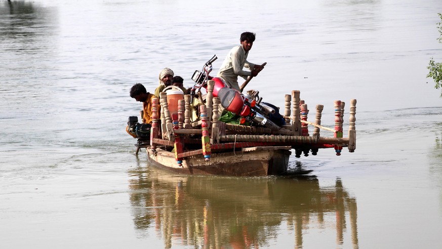 epa10145600 People transport furniture on a small boat through a flooded area following heavy rains in Larkana, Sindh province, Pakistan, 29 August 2022. According to the National Disaster Management  ...