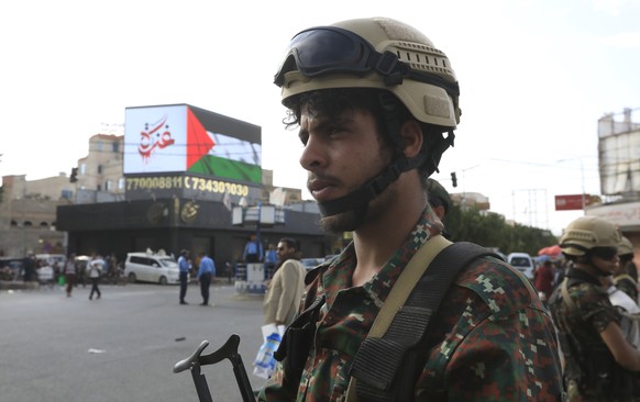 epa11348496 Houthi soldiers stand guard in front of a billboard featuring the colors of the Palestinian flag and an inscription reading in Arabic &#039;Gaza&#039;, during a protest in solidarity with  ...