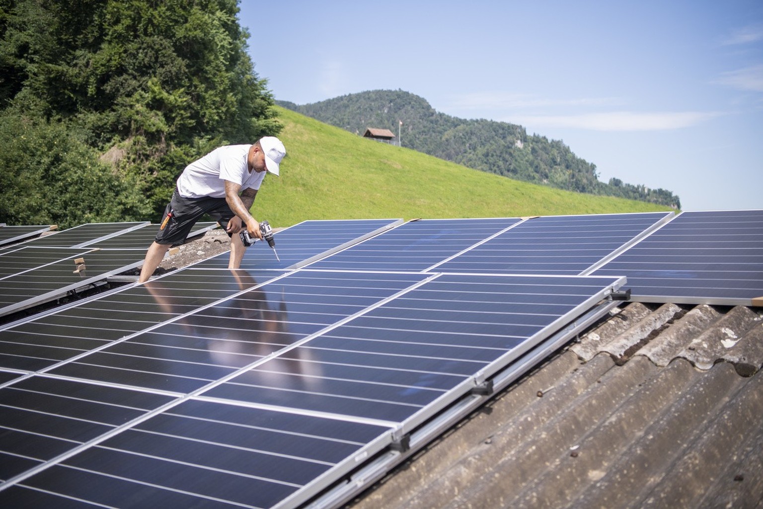 Der Solateur Jonas Huerlimann von der Firma SolarHub AG bei der Montage einer Solaranlage auf einer privat und gewerblich genutzten Halle in Stans, Kanton Nidwalden, am Donnerstag, 14. Juli 2022. Die  ...