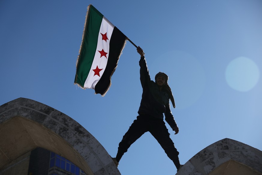 FILE - A soldier waves a Syrian flag amid celebrations a day after Syrian government troops took control of Raqqa from the Syrian Democratic Forces (SDF), at Al-Naeem roundabout in central Raqqa, nort ...