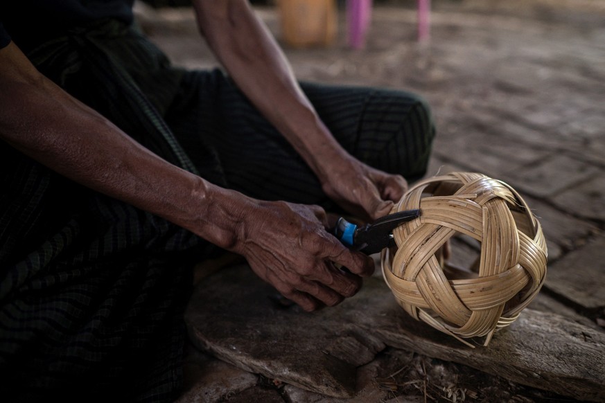 This photo taken on May 8, 2025 show a man weaving cane into a chinlone ball, used in the ancient Myanmar game considered a blend between sport and art, at a workshop in Hinthada township in the Irraw ...