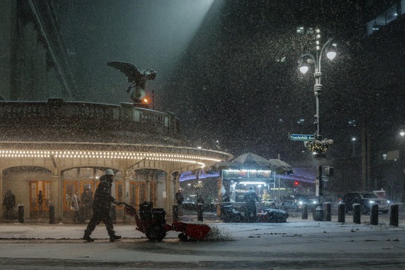 epa12770682 Worker clears snow outside of the Grand Central Station during the winter blizzard in New York, New York, USA, 22 February 2026. The National Weather Service has issued a blizzard warning  ...