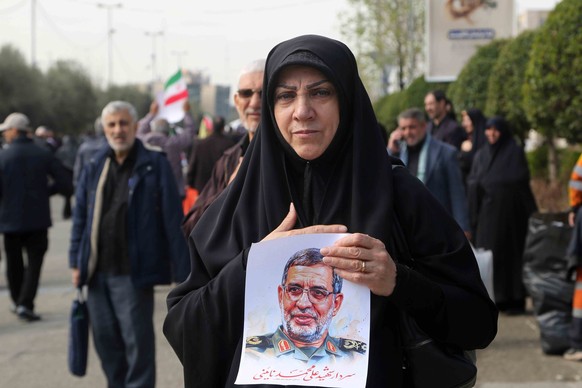 Une femme tient une image du général de brigade Ali Mohammad Naini, lors de ses funérailles.