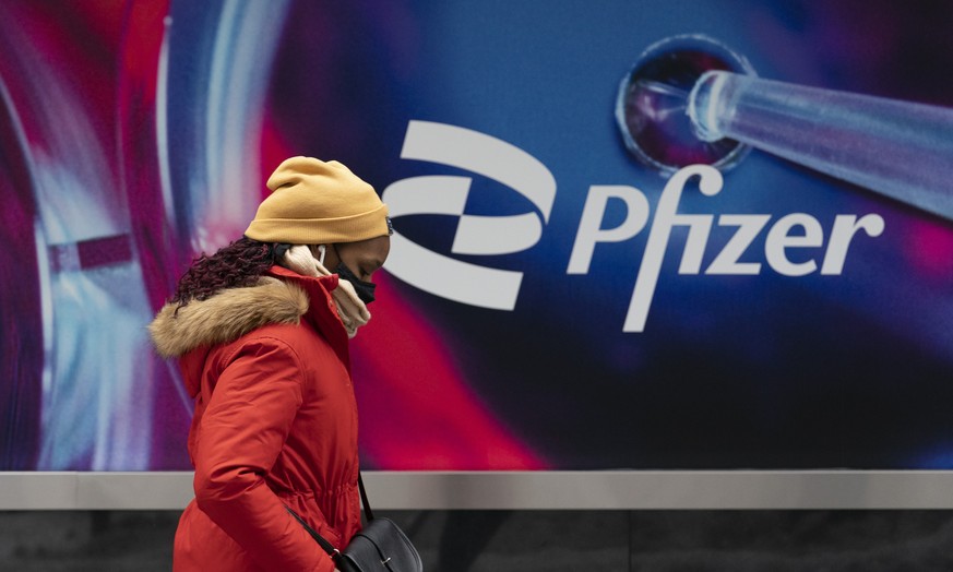 Une femme marche devant le siège du groupe Pfizer, à New York.