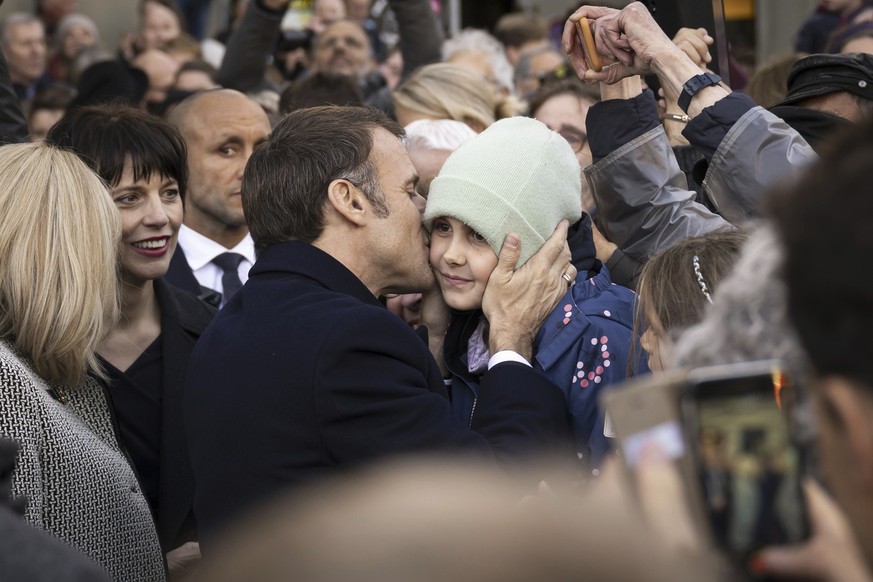 French President Emmanuel Macron, kisses a child in front of the Federal Palace, the Swiss Parliament building, in Bern, Switzerland, Wednesday, Nov. 15, 2023. French President Emmanuel Macron and his ...