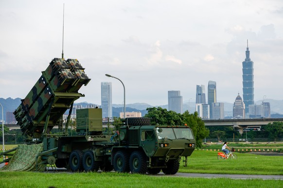 epa12239192 A person bikes past Taiwan military Patriot air defense system deployed at a park as part of the annual Han Kuang military exercises, in Taipei, Taiwan, 15 July 2025. The Taiwanese Armed F ...