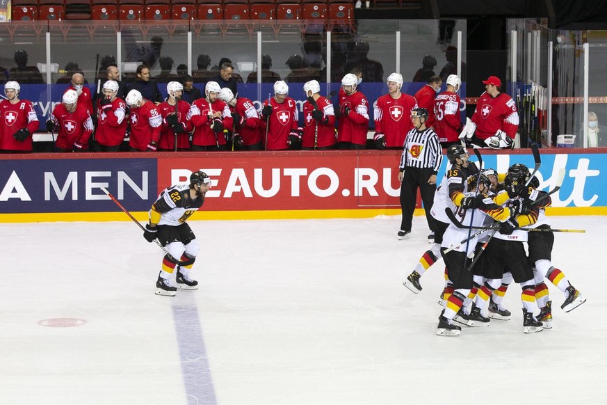 Germany&#039;s players celebrate their victory past Switzerland&#039;s players after winning during the shootout session, at the IIHF 2021 World Championship quarter final game between Switzerland and ...