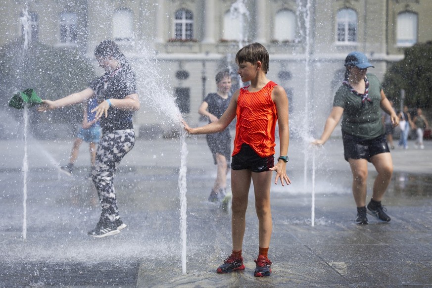 Finn, ein Pfadfinder aus Surrey, England, vorne, und seine Kolleginnen und Kollegen der &quot;Surrey Scouts&quot; kuehlen sich beim Brunnen auf dem Bundesplatz ab, am Dienstag, 22. August, 2023 in Ber ...