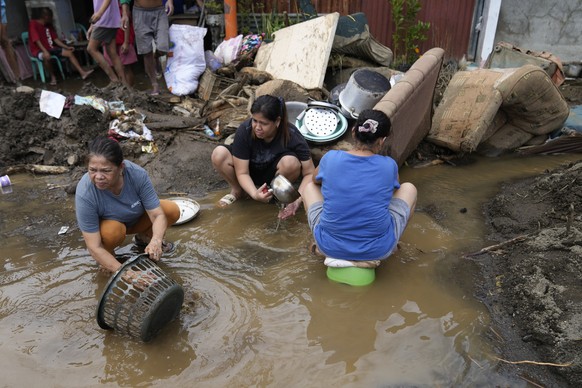 Residents try to clear out mud from their belongings after a landslide triggered by Tropical Storm Trami recently struck Talisay, Batangas province, Philippines, Saturday, Oct. 26, 2024. (AP Photo/Aar ...