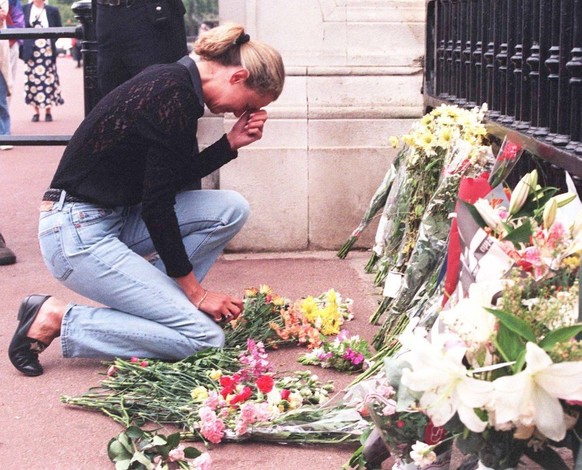 A woman weeps as she lays flowers outside Buckingham Palace in memory of Diana, Princess of Wales who had died in the early hours of the morning following a car crash in Paris, 31st August 1997. Her f ...