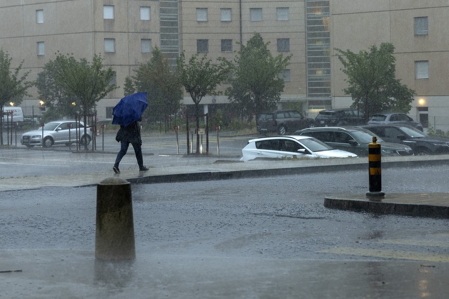 Une personne marche sous pluie abritee par son parapluie lors du passage orageux sur la ville, ce mercredi 17 aout 2022 a Geneve. (KEYSTONE/Salvatore Di Nolfi)
