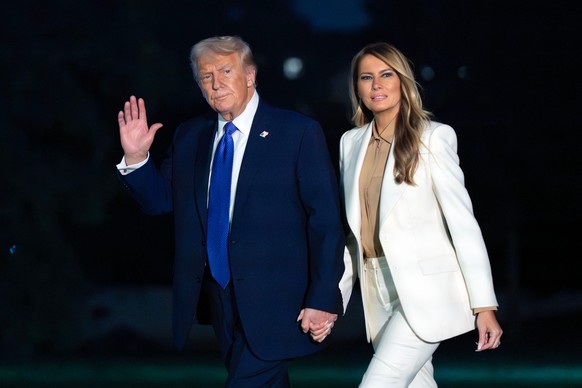 President Donald Trump waves to media while holding hands with first lady Melania Trump as they walk on the South Lawn upon their arrival to the White House, in Washington, Tuesday, Sept. 23, 2025. (A ...