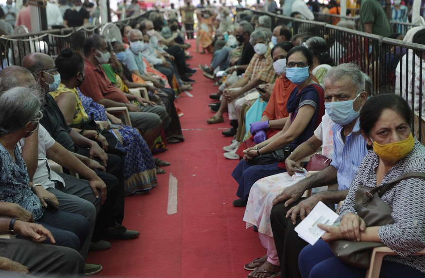 FILE - In this April 29, 2021, file photo, people wait to receive COVID-19 vaccine in Mumbai, India. A dip in the number of coronavirus cases in Mumbai is offering a glimmer of hope for India, which i ...