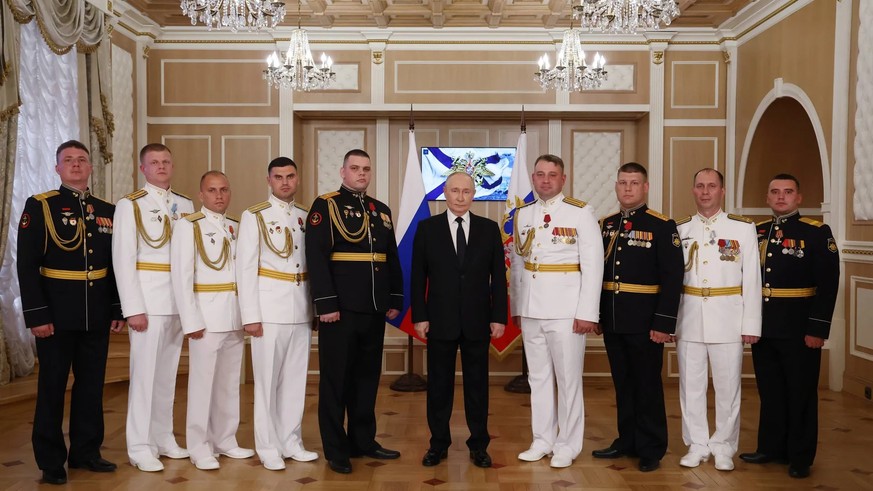 Vladimir Poutine pose ici aux côtés de représentants de la marine russe. Le chef du Kremlin souhaite renforcer ses forces navales.