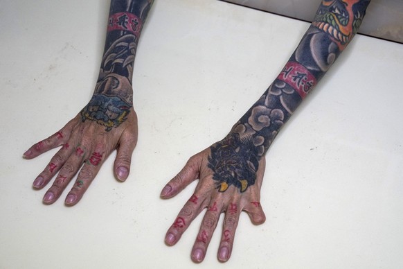 EDITORS NOTE: Graphic content / In this photograph taken on September 28, 2025, retired yakuza Mako Nishimura shows her forearm heavily inked with dragon and tiger tattoos and a missing fingertip, tha ...