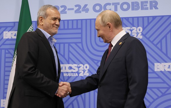 epa11677317 Russian President Vladimir Putin (R) shakes hands with Iranian President Masoud Pezeshkian before their meeting on the sidelines of the BRICS summit in Kazan, Russia, 23 October 2024. The  ...