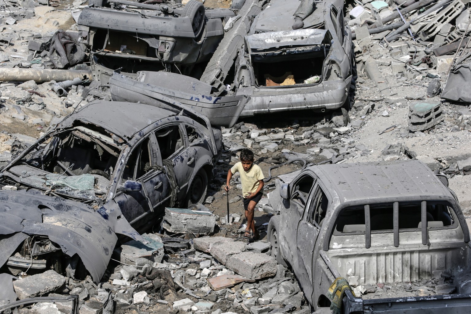 epa10909343 A Palestinian child walks past damaged cars amid the rubble of a destroyed area after Israeli air strikes in Gaza City, 09 October 2023. The Israeli army announced on 09 October, it carrie ...