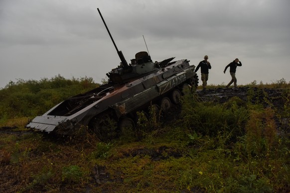 epa10186477 Ukrainian serviceman stand near a burned Russian BMP 2 APC in Kharkiv region, Ukraine, 15 September 2022. The Ukrainian army pushed Russian troops from occupied territory in the northeast  ...